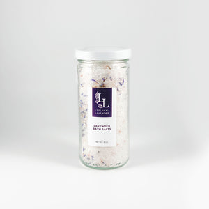 A clear glass jar filled with pink sea salts and white bath salts